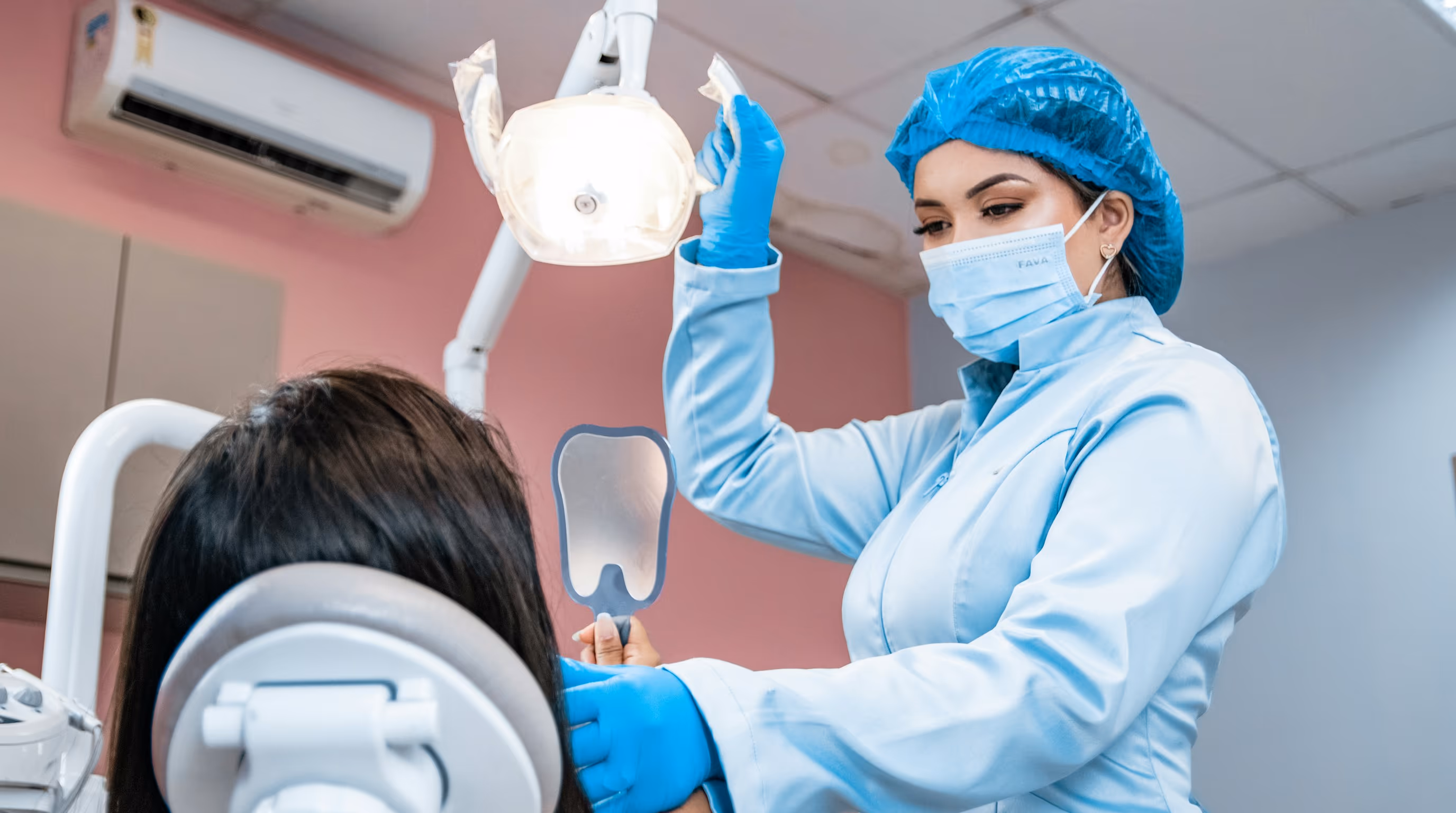 Medic stomatolog arătându-i pacientei rezultatul tratamentului în oglindă